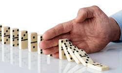 Konfliktmanagement Hand stoppt Dominosteine